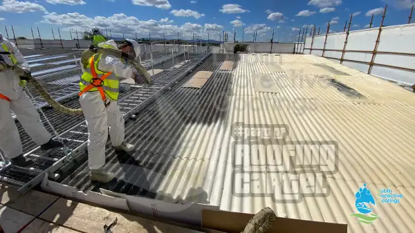 Spray foam insulation being applied to asbestos roof surface before Polyurea coating in Dublin