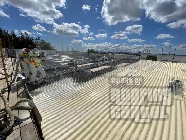 Spray foam application in progress on asbestos warehouse roof before Polyurea layer in Dublin